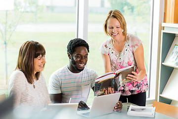 Image showing Happy Librarian Assisting Students In Library