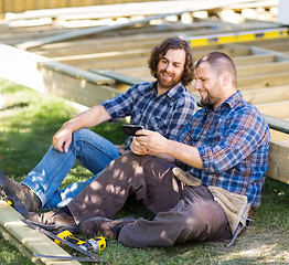 Image showing Happy Carpenters Looking At Mobile Phone At Construction Site