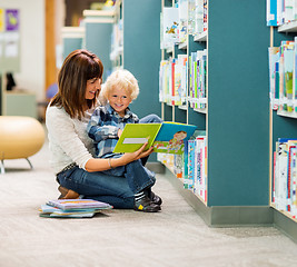 Image showing Boy And Teacher Reading Book By Bookshelf