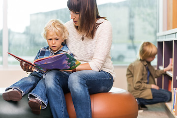 Image showing Teacher With Boy Reading Book In Library