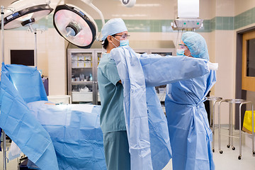 Image showing Scrub Nurse Putting Sterile Gown on Surgeon