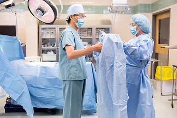 Image showing Scrub Nurse Assisting Surgeon with Gown