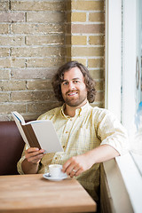 Image showing Man With Book And Coffee Cup Sitting In Cafeteria