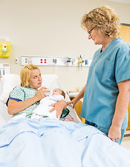 Image showing Female Nurse Looking At Patient Feeding Milk To Babygirl