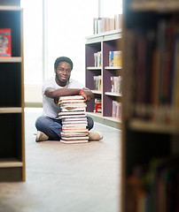 Image showing Confident Student With Stacked Books Sitting In Library