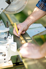 Image showing Carpenter Marking On Wood Using Ruler At Table Saw