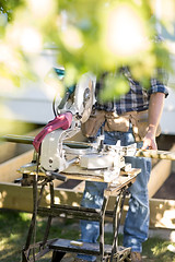 Image showing Worker Holding Wooden Plank At Table Saw