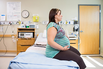 Image showing Pregnant Woman With Hands On Stomach On Hospital Bed