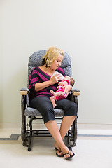 Image showing Mother Feeding Milk To Newborn Baby Girl On Chair