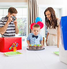 Image showing Boy Blowing Out Candles On Cake At Home