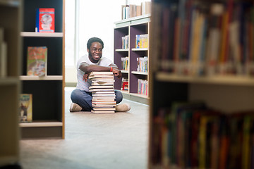 Image showing Happy Student With Stacked Books Sitting In Library