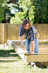 Image showing Carpenter Cutting Wood With Saw At Construction Site