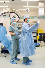 Image showing Nurse Assisting Doctor In Wearing Operation Gown