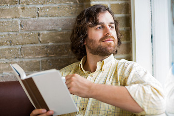 Image showing Man With Book Looking Through Window In Coffeeshop