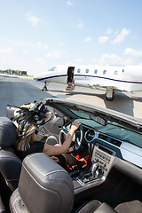 Image showing Woman In Convertible With Private Jet At Terminal