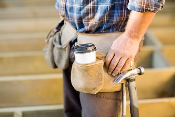 Image showing Disposable Coffee Cup And Hammer On Carpenter's Tool Belt