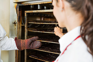 Image showing Workers Removing Dried Meat Slices From Oven At Shop