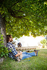 Image showing Worker With Eyes Closed Leaning On Tree Trunk