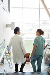 Image showing Doctor And Nurse Conversing While Walking Down Stairs In Hospita