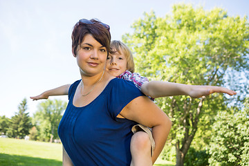 Image showing Beautiful Mother Carrying Son On Back At Park