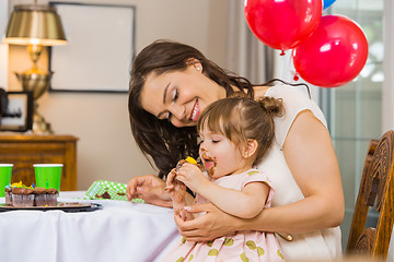 Image showing Mother Looking At Birthday Girl Eating Cupcake