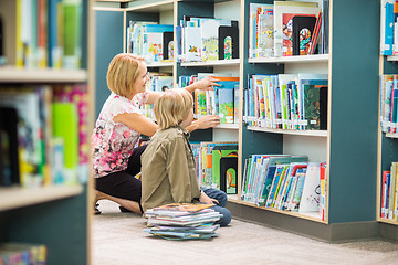 Image showing Teacher Assisting Boy In Selecting Books In Library