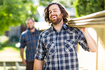 Image showing Carpenter With Coworker Carrying Planks While Laughing
