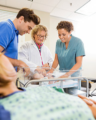 Image showing Medical Team Examining Babygirl By Man With Mother In Foreground