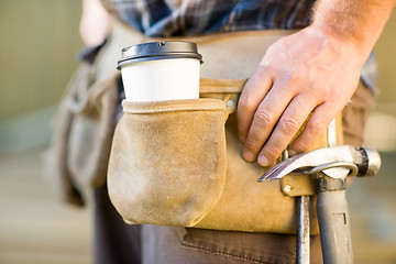 Image showing Disposable Coffee Cup And Hammer On Carpenter's Tool Belt