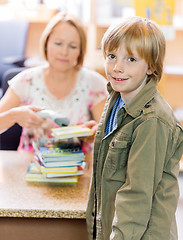 Image showing Boy With Librarian Scanning Books At Library Counter