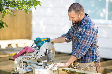 Image showing Carpenter Cutting Wood Using Table Saw At Construction Site