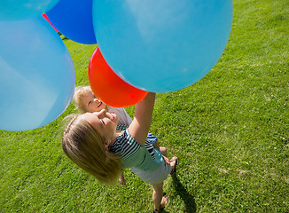 Image showing Mother And Daughter Holding Colorful Balloons In Park