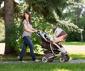 Image showing Beautiful Mother Pushing Baby Carriage In Park