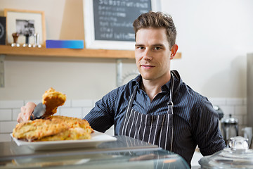 Image showing Confident Cafe Owner Holding Sweet Food In Tongs