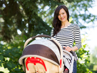 Image showing Beautiful Woman Pushing Stroller In Park