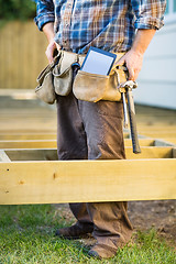 Image showing Carpenter With Tablet Computer And Hammer In Tool Belt