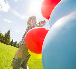 Image showing Boy With Balloons Walking In Green Meadow