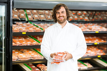 Image showing Happy Salesman Holding Meat Packages At Counter