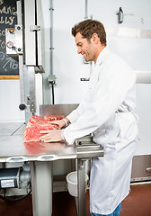 Image showing Smiling Butcher Slicing Meat On Bandsaw