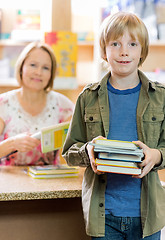 Image showing Schoolboy Checking Out Books From Library