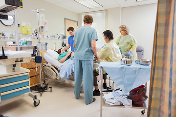 Image showing Medical Team Operating Pregnant Woman While Husband Standing By