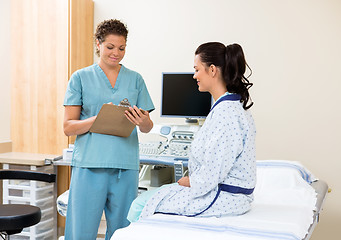 Image showing Nurse Writing Notes With Patient Sitting On Bed