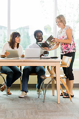 Image showing Librarian And Students Looking At Book In Library