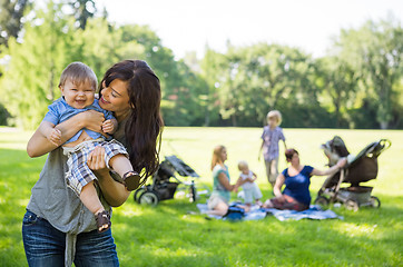 Image showing Mother Carrying Cheerful Baby Boy At Park