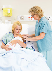 Image showing Nurse Assisting Woman In Breast Feeding Baby In Hospital