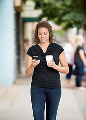 Image showing Woman With Coffee Cup Using Smartphone On Pavement