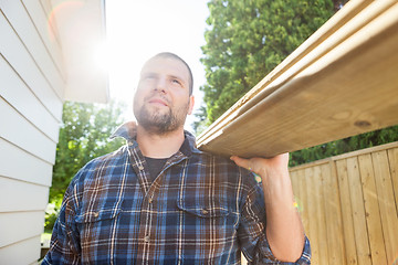 Image showing Carpenter Carrying Planks While Looking Away At Site