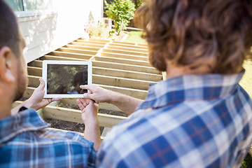 Image showing Carpenter Pointing At Digital Tablet While Coworker Holding It