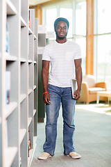 Image showing Student With Digital Tablet Standing By Bookshelf In Library