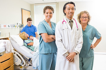 Image showing Confident Medical Team With Newborn Baby And Parents In Backgrou